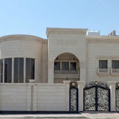فيلا بيضاء ببرج دائري وبوابة سوداء مزخرفة